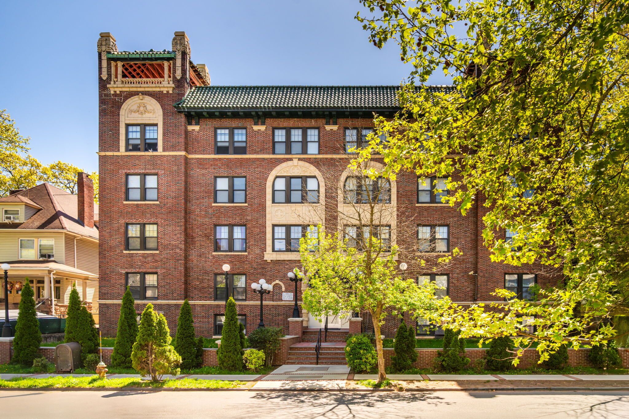 A multi-story brick building with a symmetrical facade, a central entrance with steps, and a small porch area.