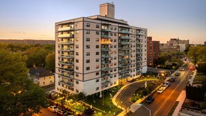 Un hotel de varios pisos con balcones, una zona de estacionamiento y vistas del paisaje urbano circundante.