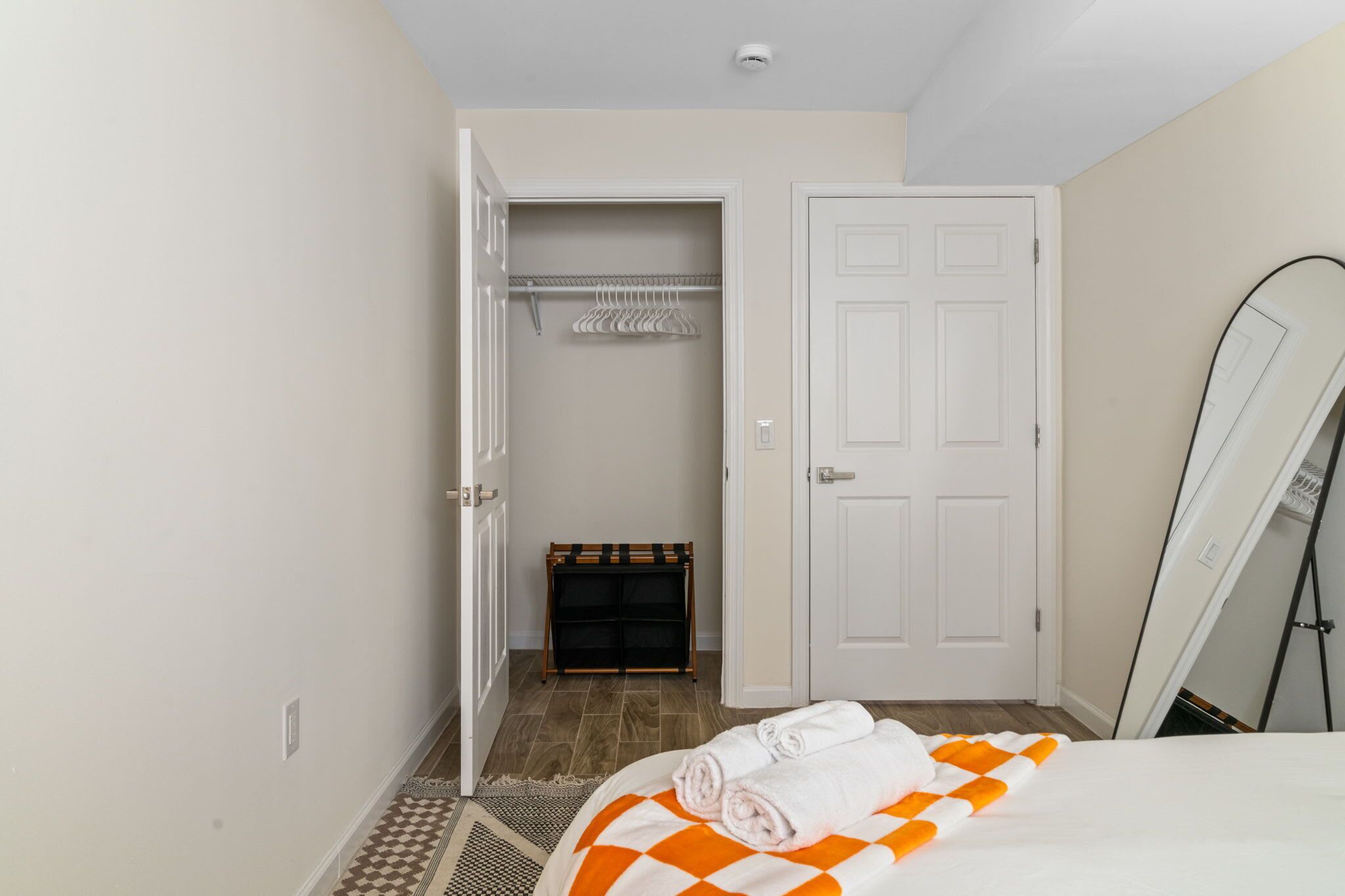 A hotel room with a bed, a closet, and a door.