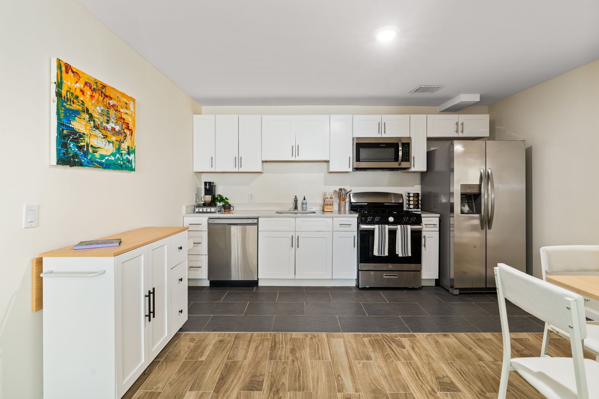A modern kitchen with white cabinets, stainless steel appliances, and a wooden countertop.
