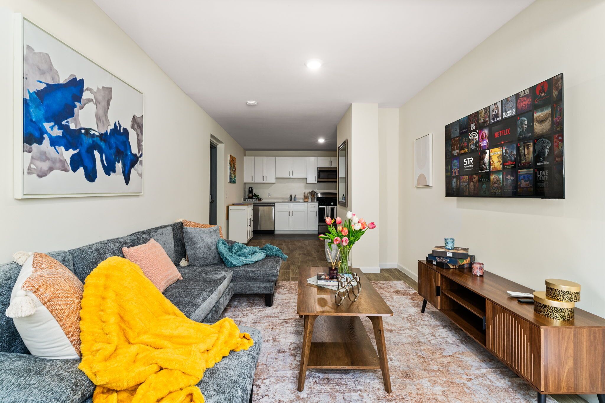 A living room with a sofa, coffee table, and a TV wall art.