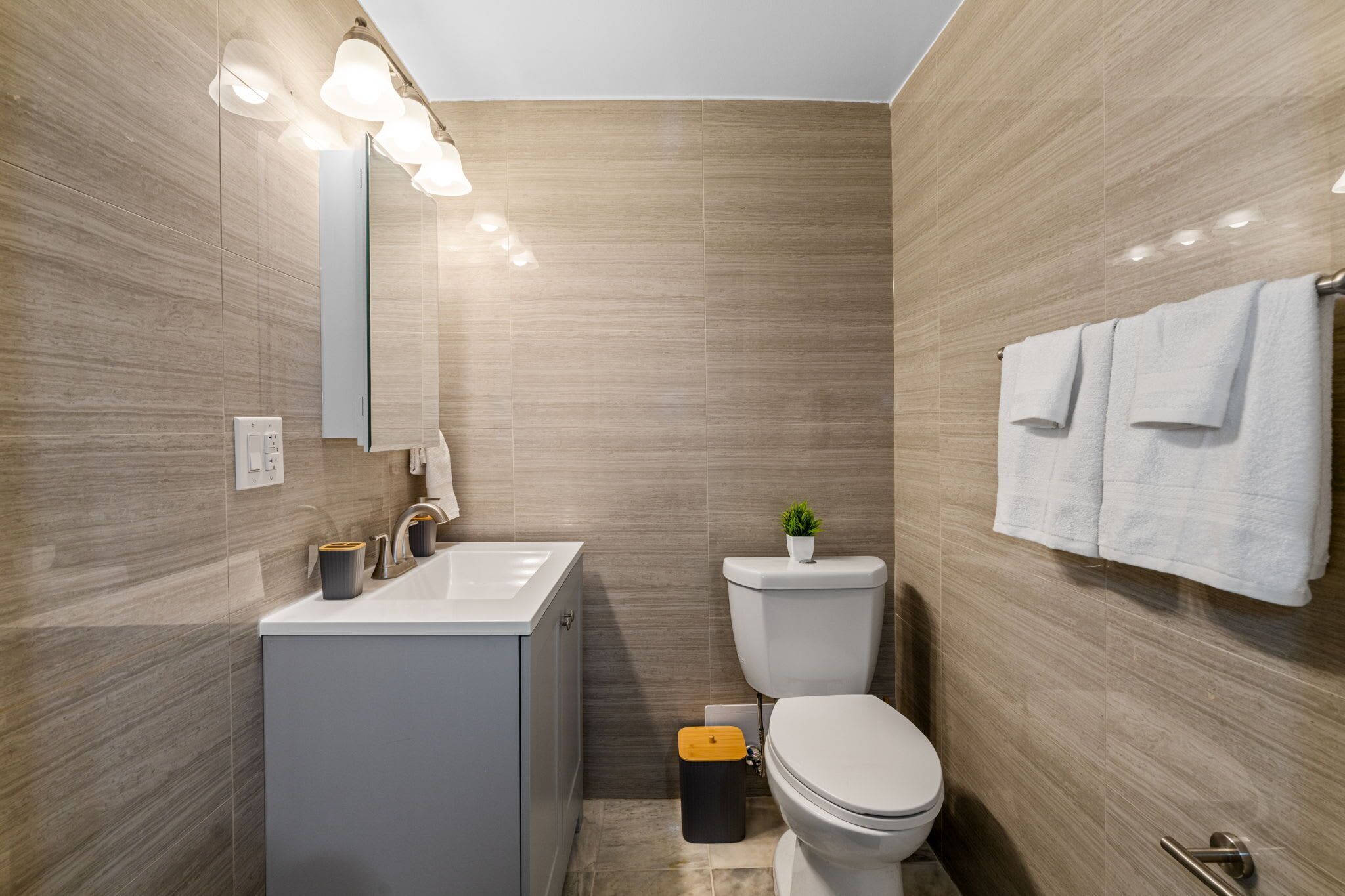 A modern bathroom with a sink, mirror, toilet, and towel rack.