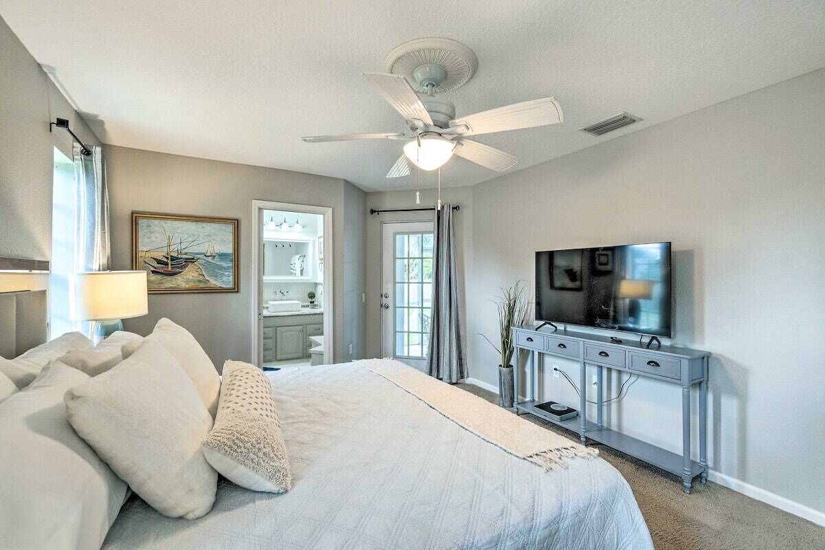 Une chambre à coucher avec un lit, un ventilateur de plafond, une télévision et une commode.
