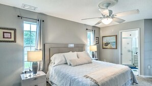 A bedroom with a bed, nightstands, a ceiling fan, and a door. - Stylish Coastal  Cottage Near Downtown Punta Gorda (Punta Gorda)