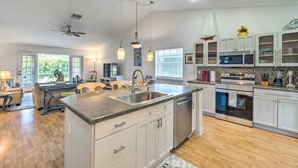 A modern kitchen with a central island, built-in appliances, and a dining area with chairs. - Stylish Coastal  Cottage Near Downtown Punta Gorda (Punta Gorda)