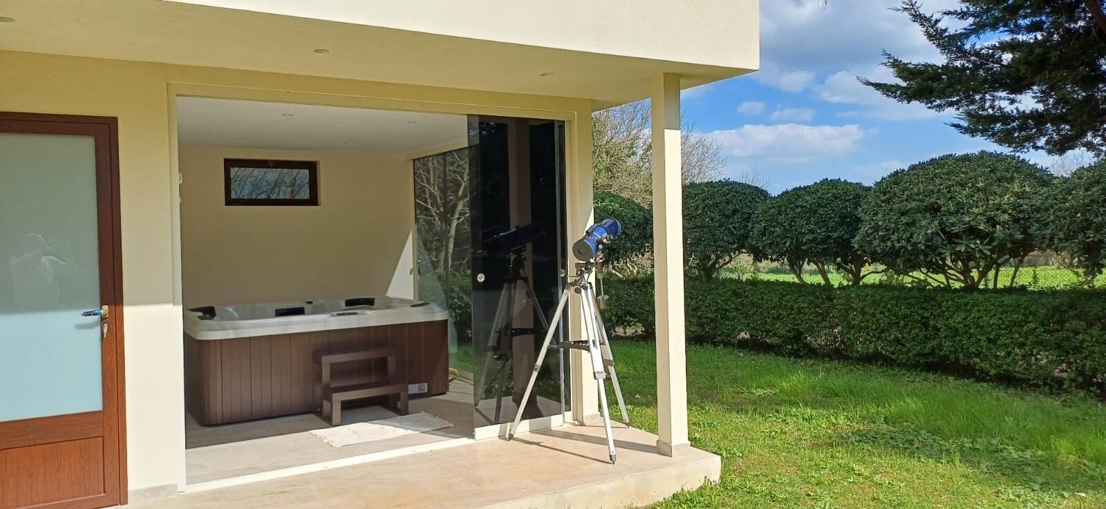 A modern building with a covered outdoor area, a hot tub, and a telescope.