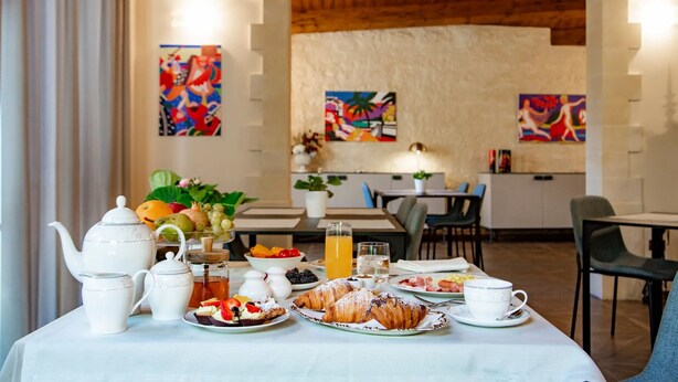 A breakfast setup with a table, teapot, cups, and pastries. - Relais Villa Caia (Noto)