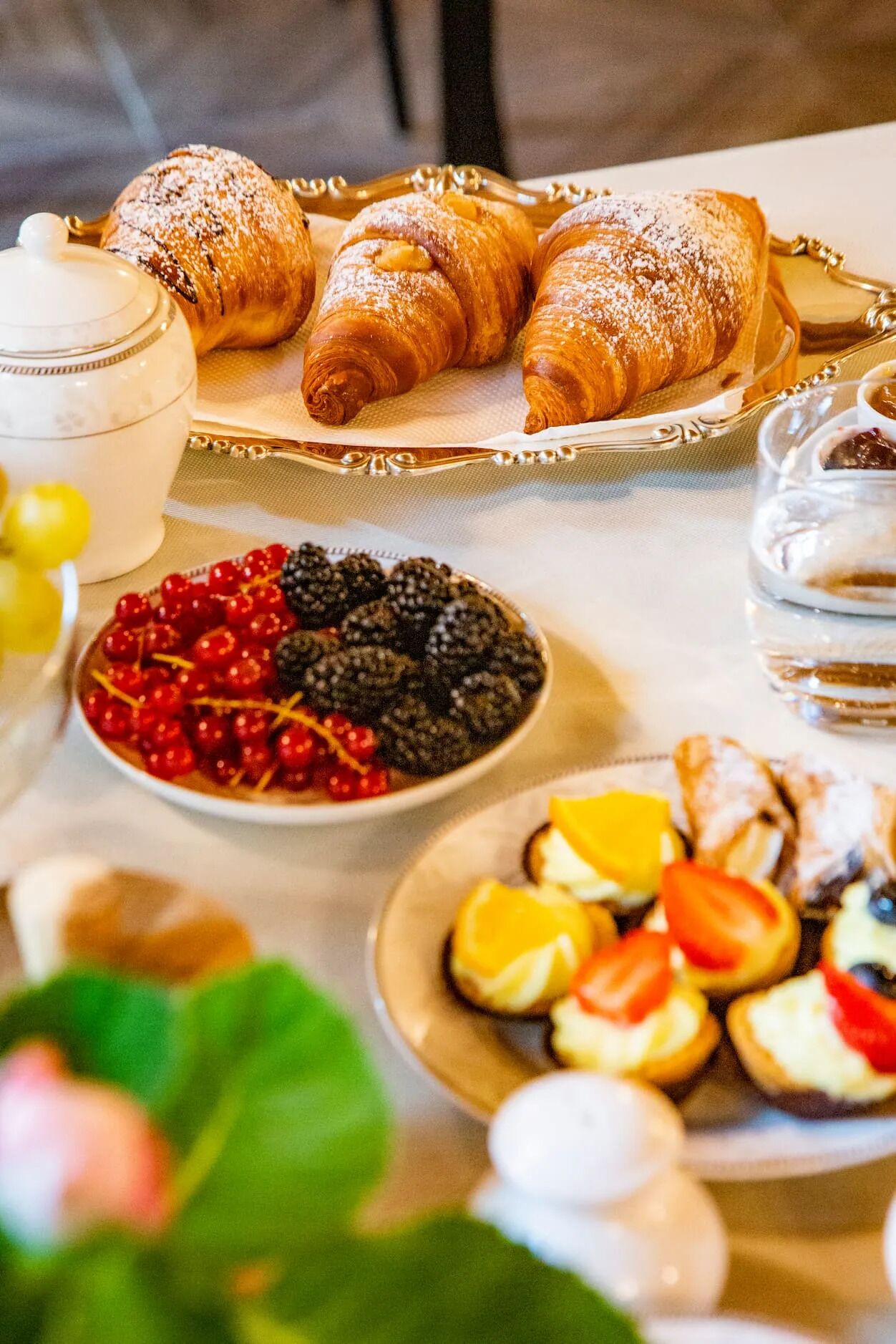 Une table avec des pâtisseries, des fruits et un verre d’eau.
