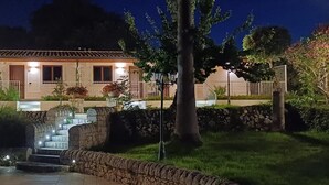 A two-story house with a stone staircase leading to a small pool, surrounded by greenery. - Relais Villa Caia (Noto)