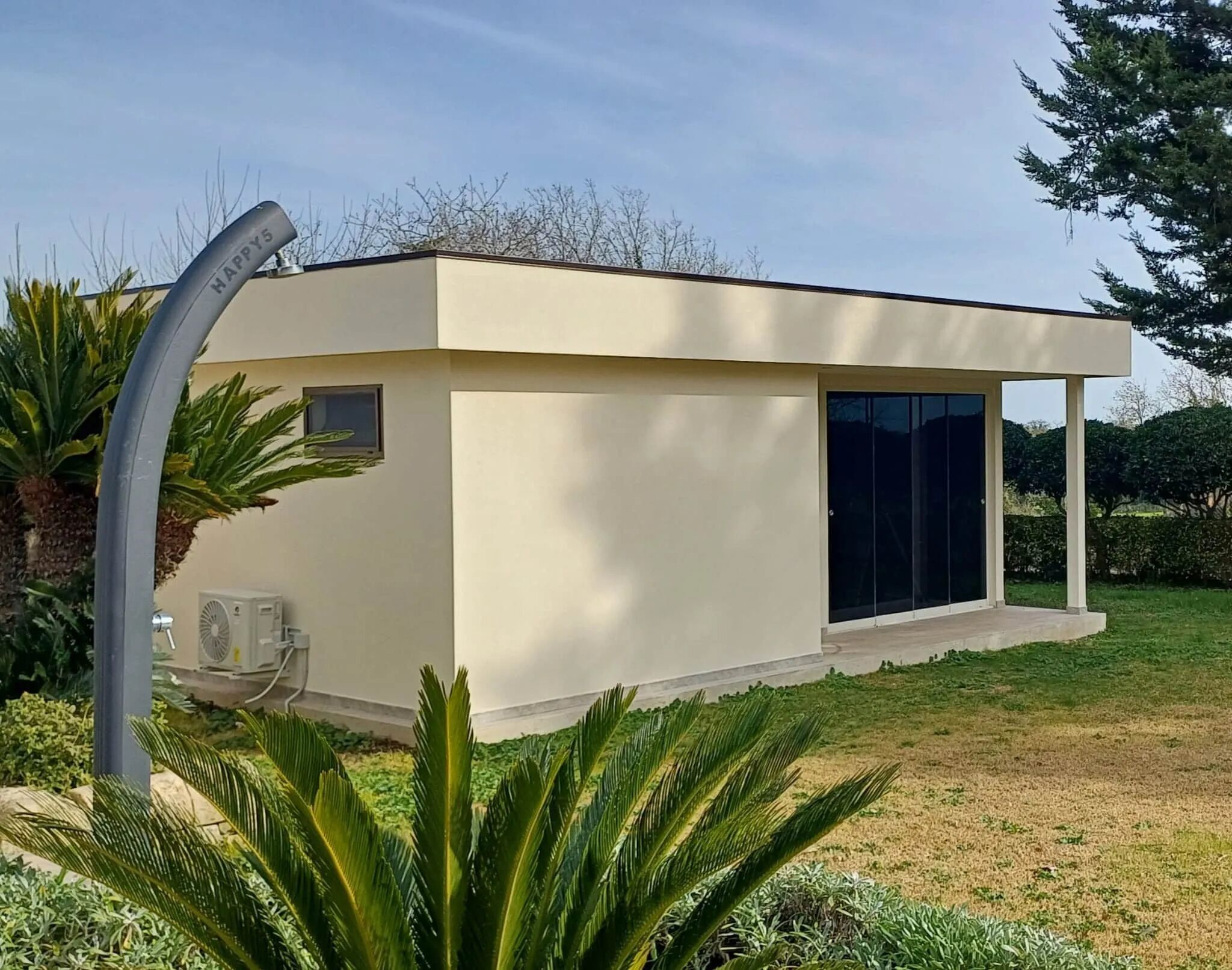 Un edificio moderno con tetto piatto, ampie finestre e una zona esterna coperta.