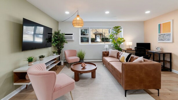 Una sala moderna con una televisión de pantalla plana, un sofá, una mesa de centro y un mueble para televisión.