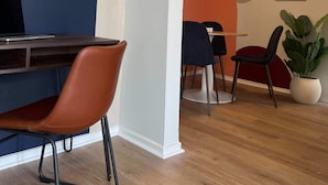 A modern interior with a desk, chairs, a mirror, and a plant.
