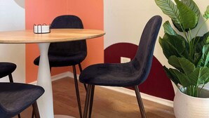 A modern dining area with a round wooden table, black upholstered chairs, and a potted plant.