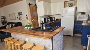 Una cocina con una isla central, taburetes de bar, armarios blancos, un microondas y una estufa.
