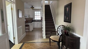 Un pasillo con una escalera, una zona de cocina y un comedor.