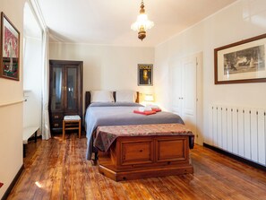 A bedroom with a wooden bed, a nightstand, a chair, a radiator, and a door. - La Quiete by Interhome (Verbania)