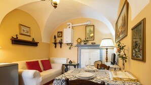 A cozy dining area with a table set for two, a sofa with red cushions, a radiator, and a fireplace. - La Quiete by Interhome (Verbania)