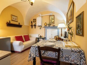 A cozy dining area with a table set for two, a sofa with red cushions, a radiator, and a fireplace. - La Quiete by Interhome (Verbania)