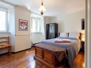 Een slaapkamer met een bed, een houten bankje, een kledingkast en een raam.