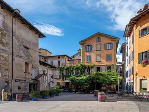 A courtyard with outdoor seating, a building with a sign 'Il Bar del Castello', and a clear blue sky. - La Quiete by Interhome (Verbania)
