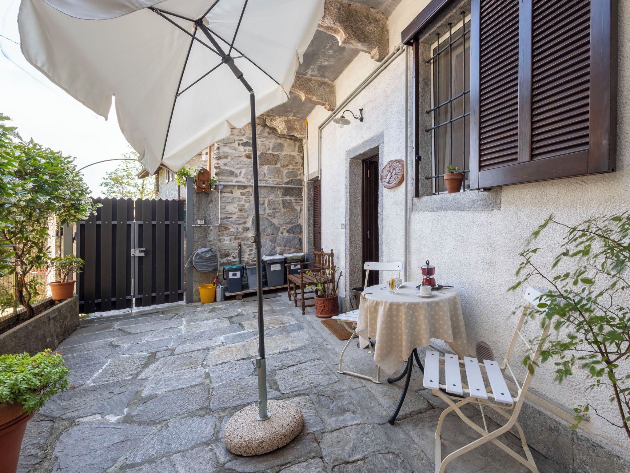 Un edificio de piedra con patio, asientos al aire libre y una mesa con mantel blanco.