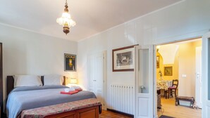 A bedroom with a bed, bedside table, lamp, and a door leading to a dining area. - La Quiete by Interhome (Verbania)