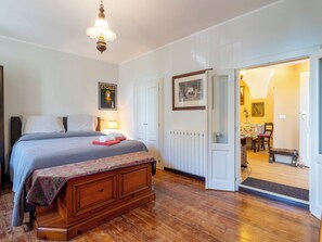 A bedroom with a bed, bedside table, lamp, and a door leading to a dining area. - La Quiete by Interhome (Verbania)