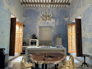Ein Essbereich mit einem runden Holztisch, Stühlen, einer Chandelier und einer Küche im Hintergrund.