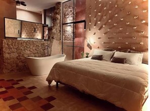 Ein Schlafzimmer mit einem großen Bett, einer Badewanne und einer Steinwand.