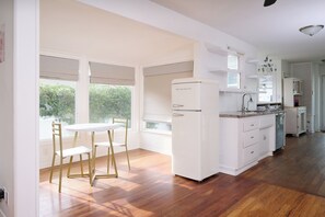Una cuina moderna amb armaris blancs, una illa integrada i una zona de dinar amb taula i caires.
