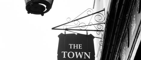 A black and white photo of a street lamp and a sign reading 'THE TOWN HOUSE.'