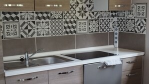 A modern kitchen with a stainless steel sink, wooden cabinets, and patterned backsplash tiles. - House by the river, 12 kms from the sea, shops, 10 km from Caen (Cairon)