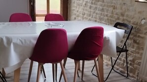 A room with a table and chairs, a small stool, and a radiator. - House by the river, 12 kms from the sea, shops, 10 km from Caen (Cairon)