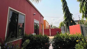 Ein rotes Gebäude mit Fenster, einer Tür und einem kleinen Garten mit Gras und Pflanzen.