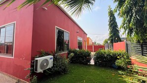 Ein rotes Gebäude mit kleinem Garten, einem Fenster und einer Klimaanlage.