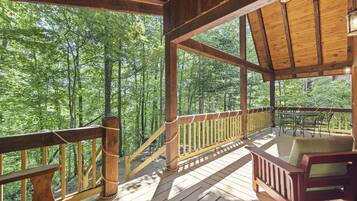 A wooden deck with a railing, a table, and a chair.