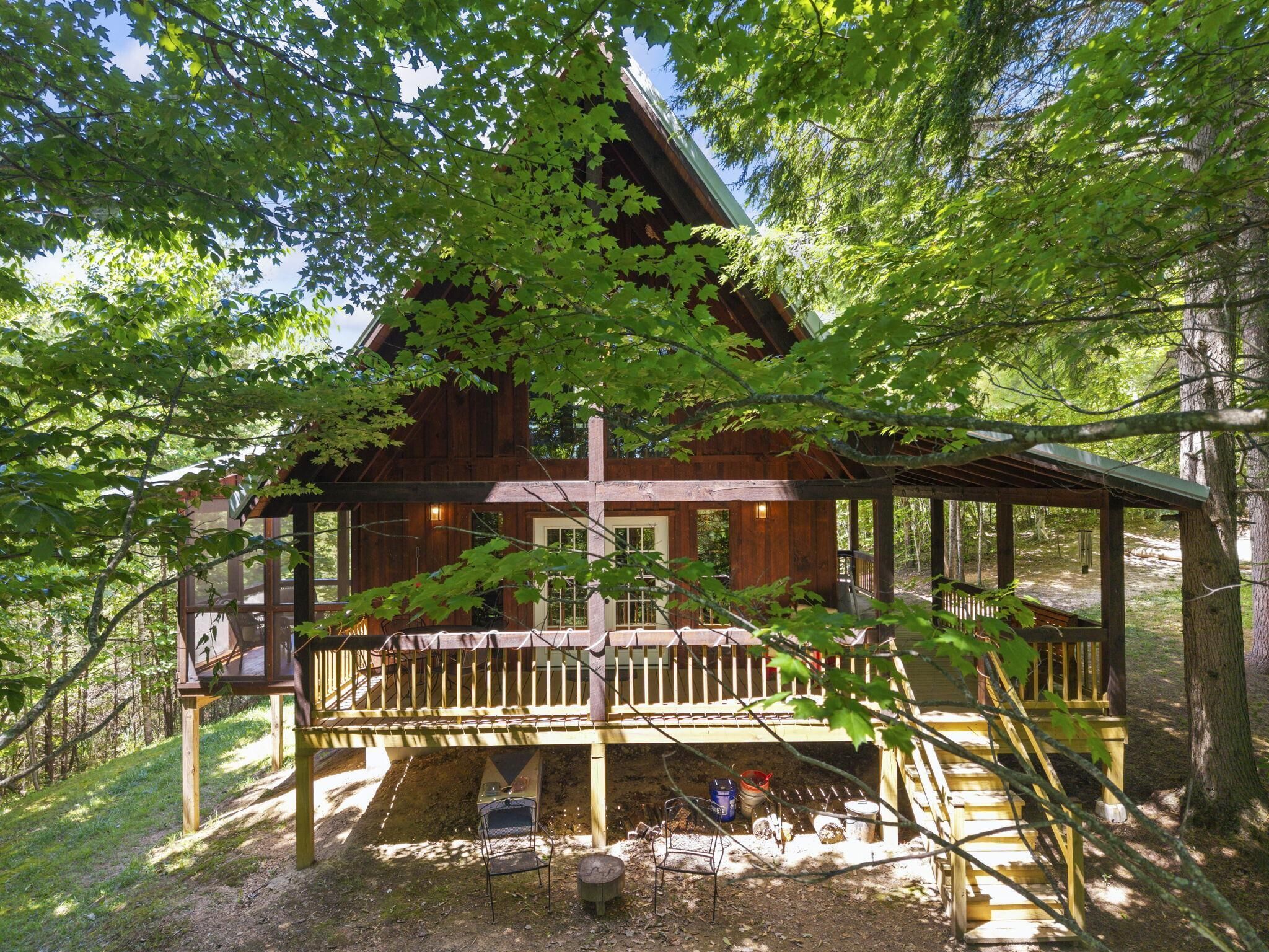 Una baita di legno con veranda, immersa tra gli alberi.