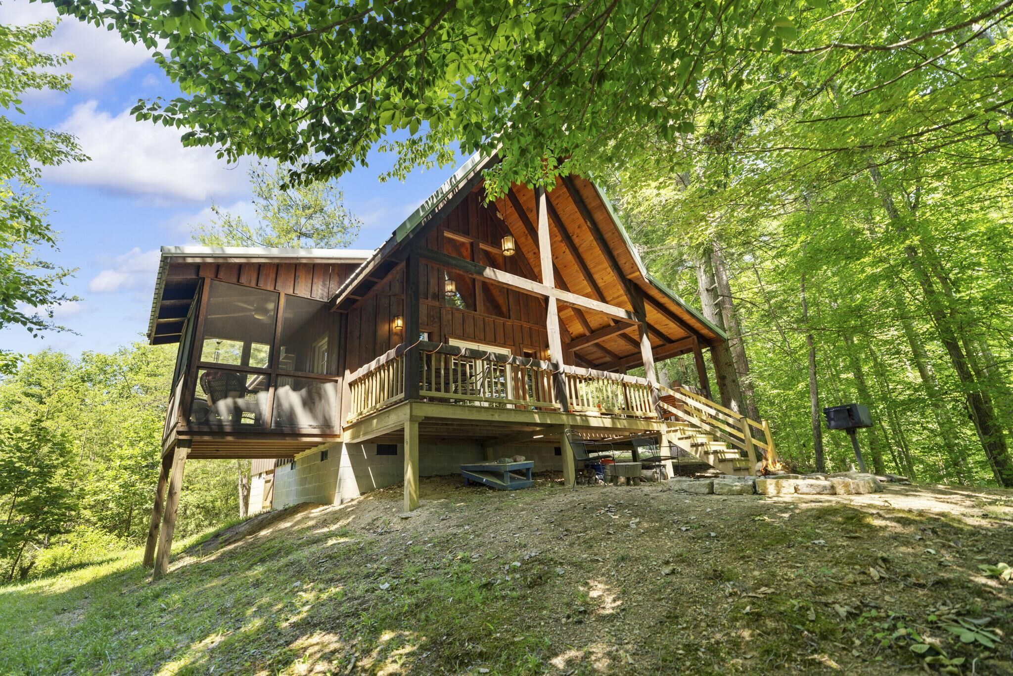 A wooden cabin with a balcony, surrounded by trees.