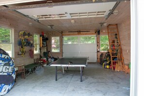 Eine Garage mit Tischtennisplatte, Sportgeräten und einer Leiter.