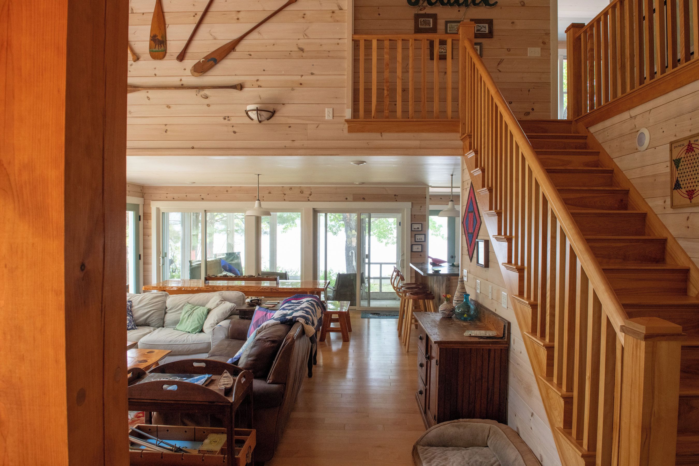 A spacious living room with a wooden staircase, a sofa set, and a dining area.