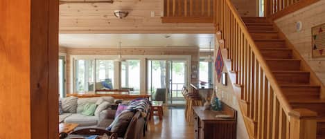 A spacious living room with a wooden staircase, a sofa set, and a dining area.