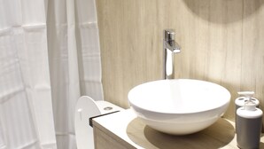 A bathroom with a white toilet, a wooden vanity with a sink, a mirror, and a shower curtain.
