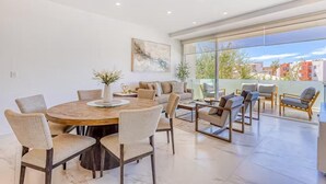 Ein modernes Wohnzimmer mit Essbereich, großen Fenstern und Blick auf die Stadt.