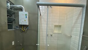 Ein modernes Badezimmer mit einer gläsernen Dusche, einem weißen Waschbecken und einem kleinen Topfpflanzen.