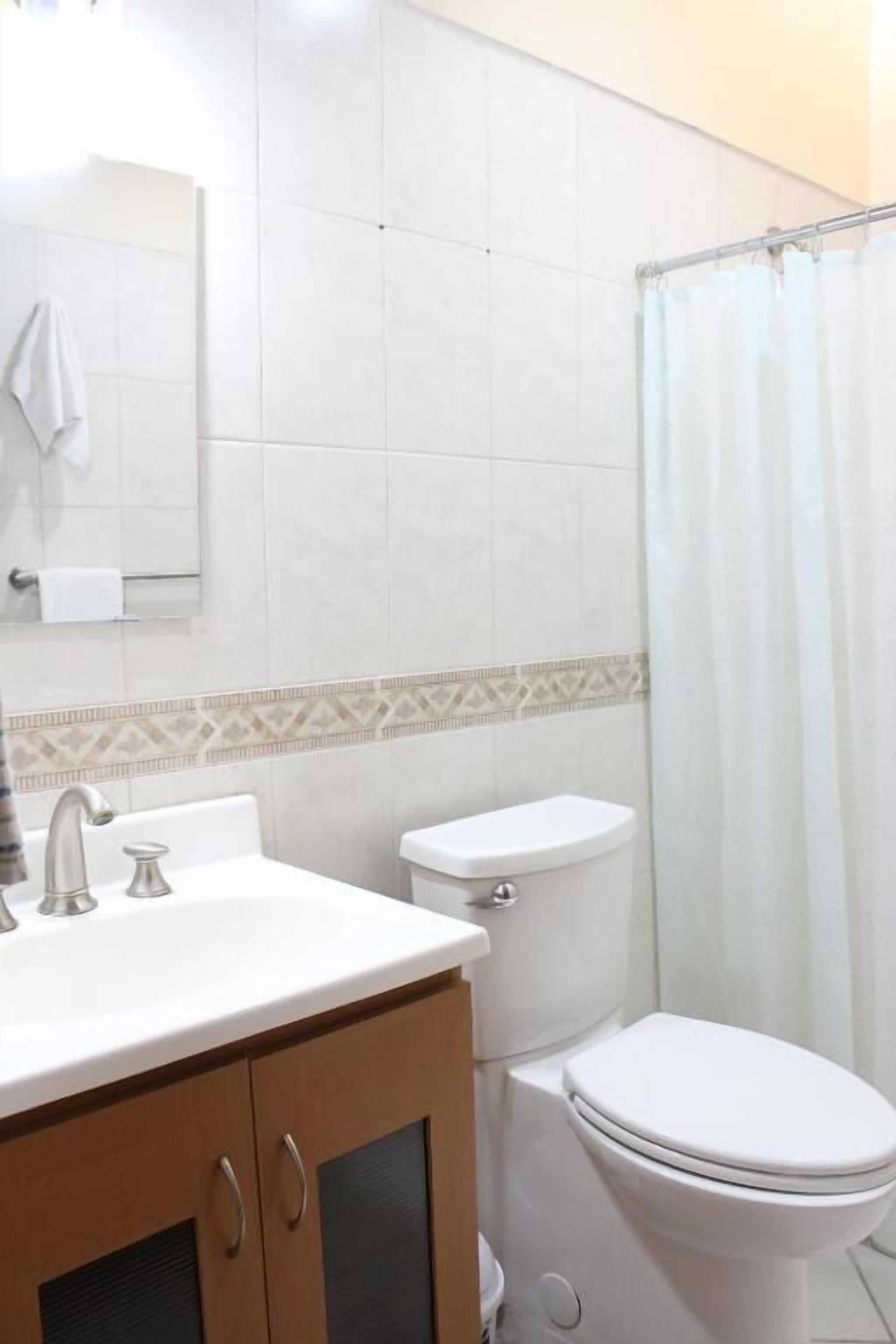 Une salle de bain avec un lavabo, des toilettes et un rideau de douche.
