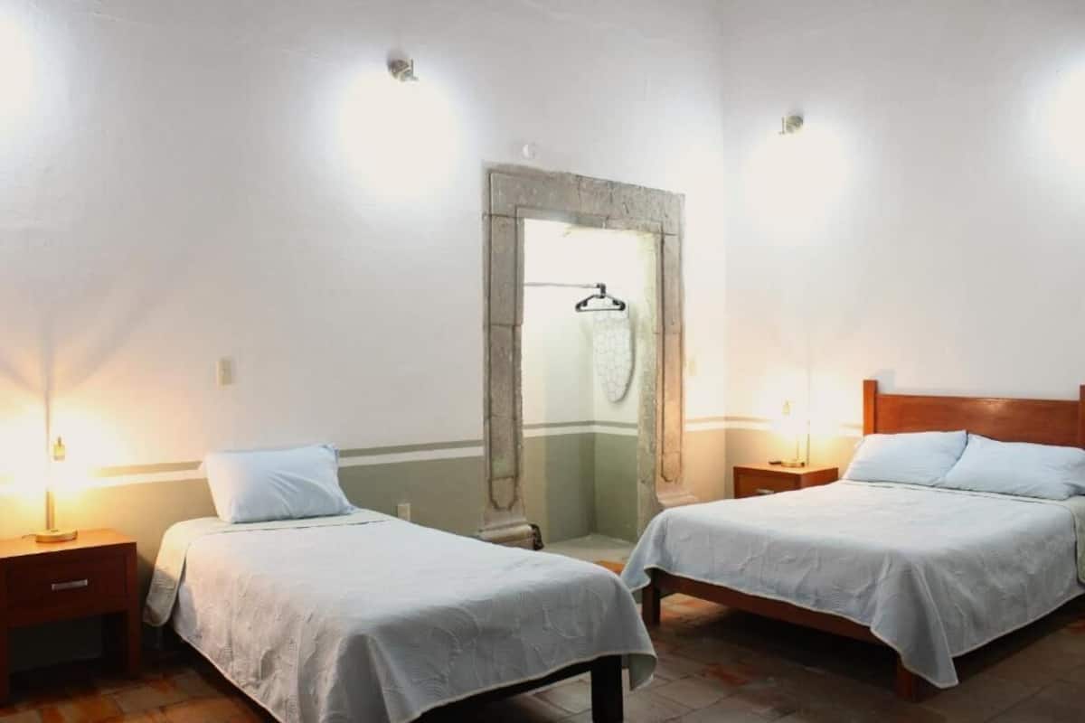 A room with two beds, a mirror, a hanging shower curtain, and bedside lamps.
