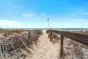 A beach pathway leading to the ocean, with a wooden fence on one side and a flag on the other. - Pet-Friendly Beach Home, 2 Pools, Bunks (Gulf Shores)
