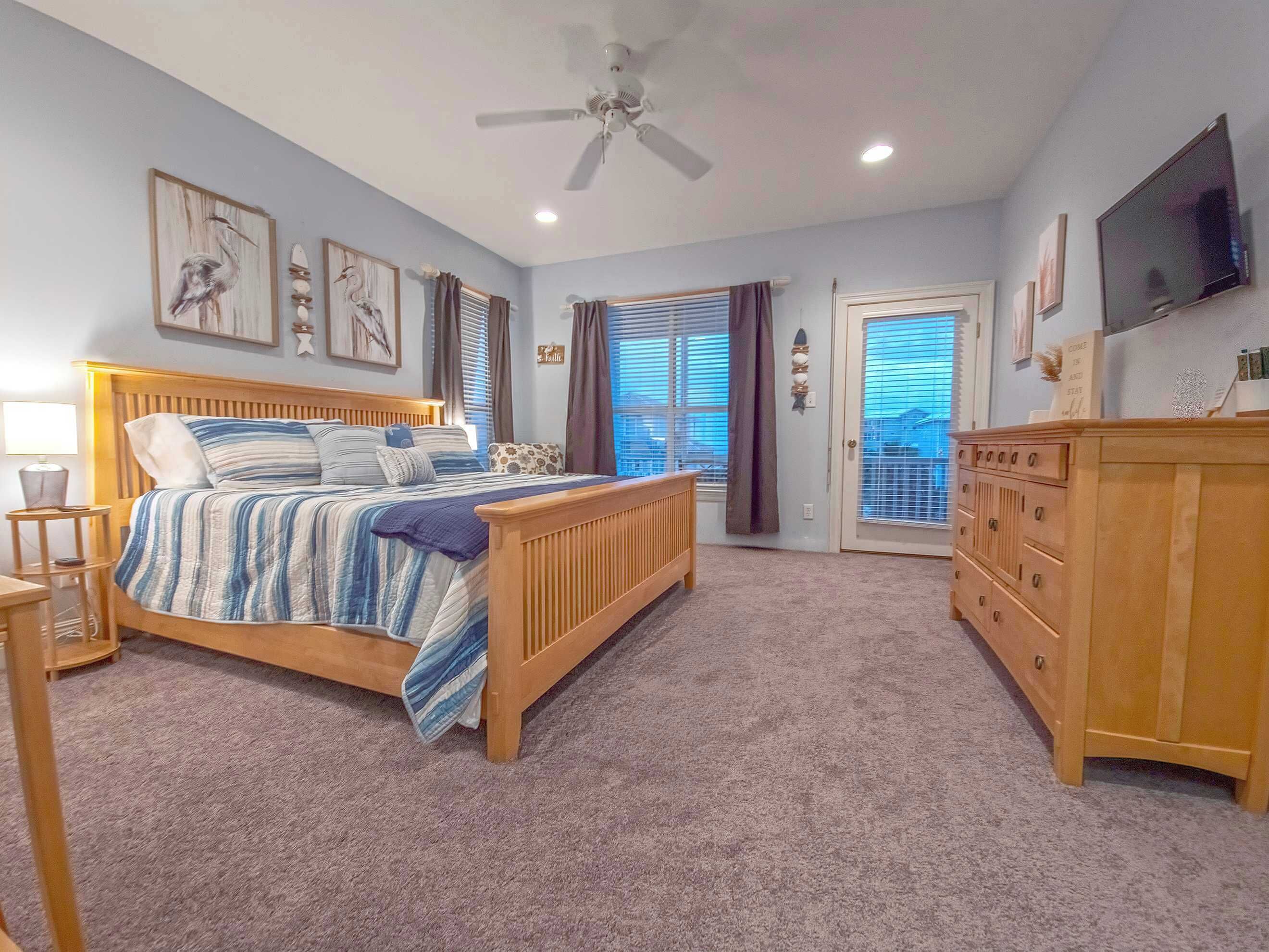 Ein Schlafzimmer mit Bett, Kommode, Deckenventilator und Kunstwerken an den Wänden.