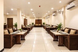 A hotel dining area with multiple tables and sofas, air conditioning units, and a ceiling light fixture. - Aceotel Select Florence, Ujjain (Ujjain)