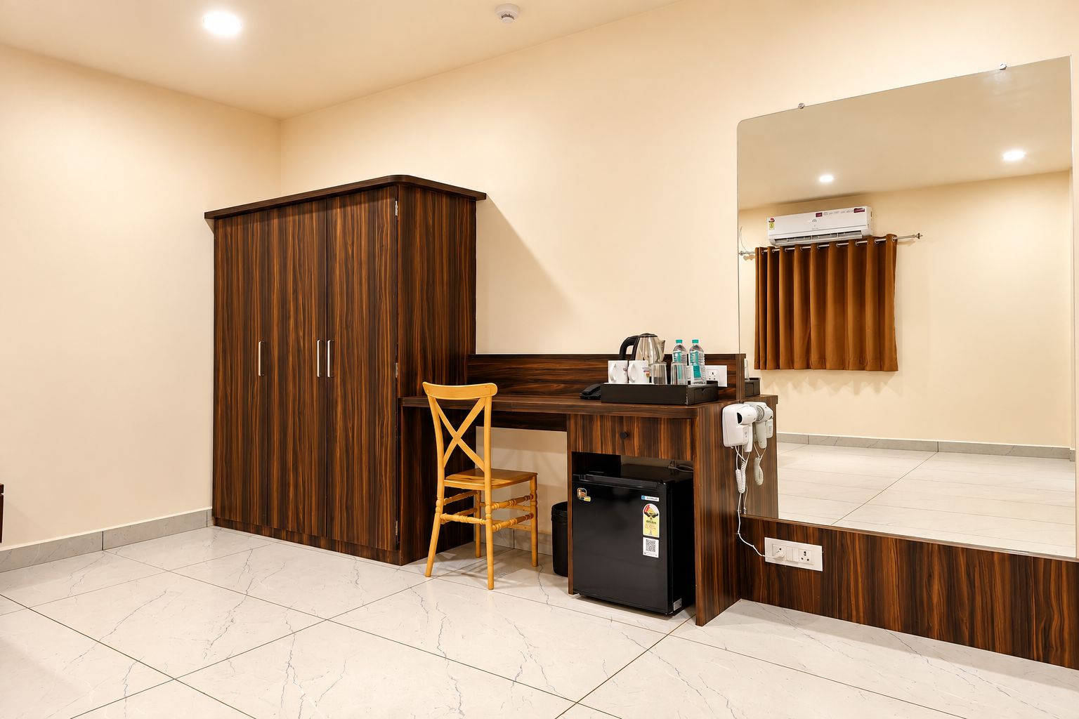 Un baño de hotel con un armario de madera, un escritorio con una silla, un espejo y un secador de pelo.